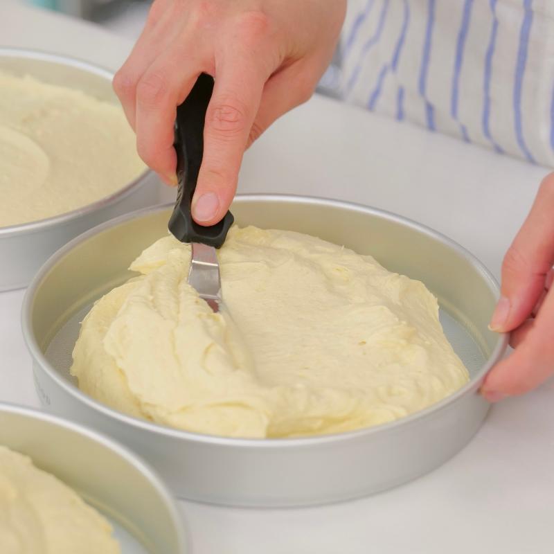 Cooling cake on wire rack: A woman gently places a freshly baked cake onto a wire cooling rack, ensuring even airflow for optimal cooling and crack prevention.