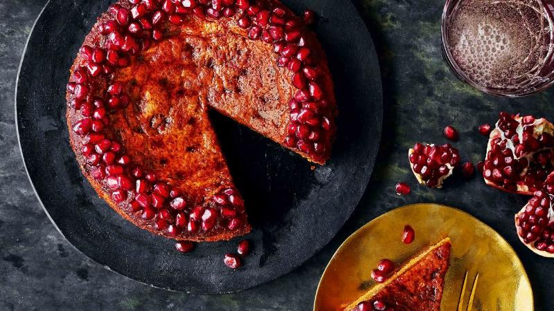 Decorating a pomegranate cake with fresh arils, adding a vibrant touch.