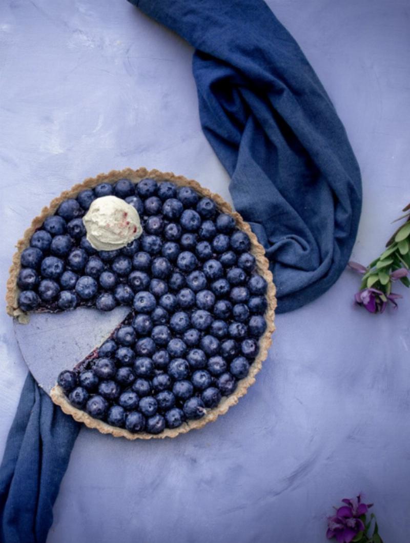 Slice of blueberry pie served on a plate with a scoop of vanilla ice cream