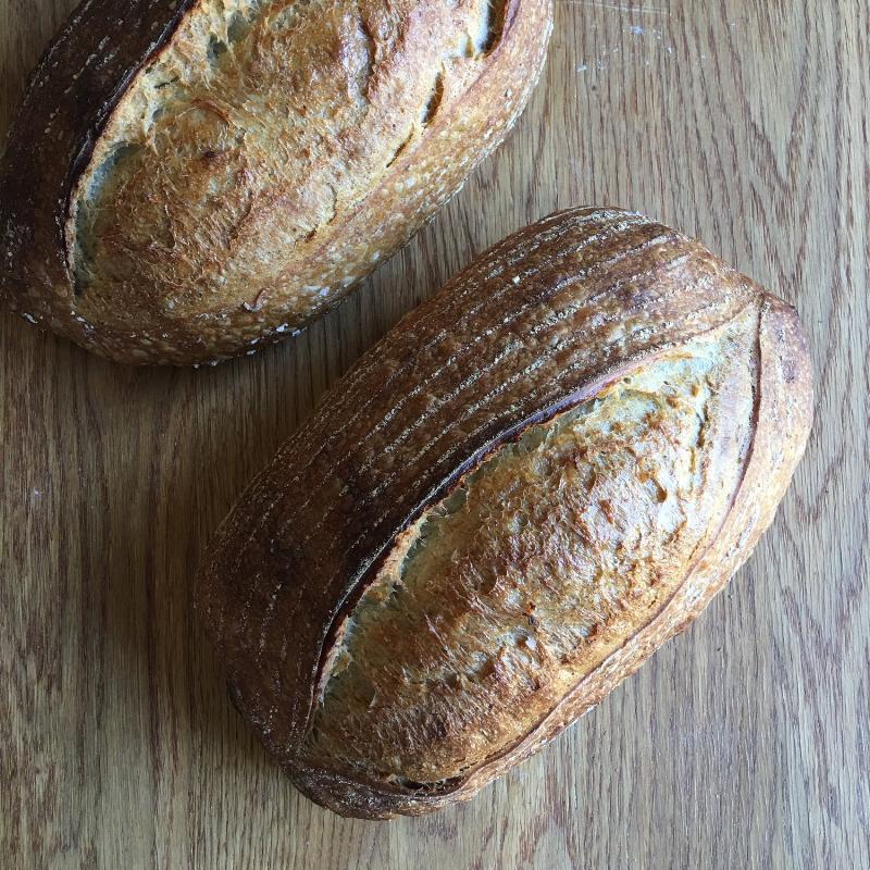 A freshly baked loaf of einkorn sourdough bread cooling on a wire rack