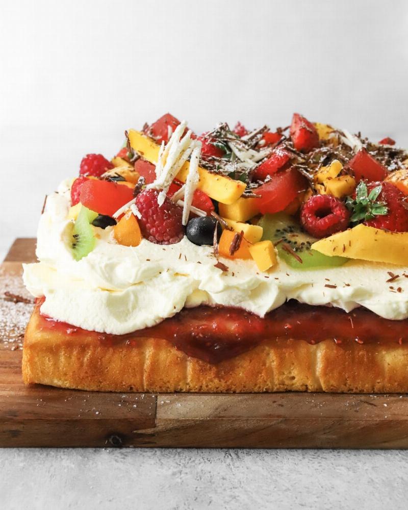 Fluffy sponge cake decorated with fresh berries and whipped cream