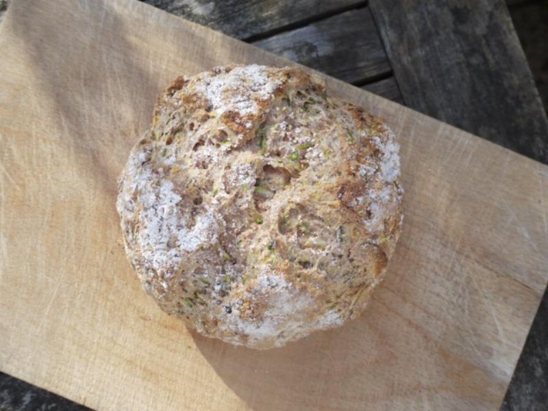 A loaf of freshly baked zucchini bread cooling on a wire rack.