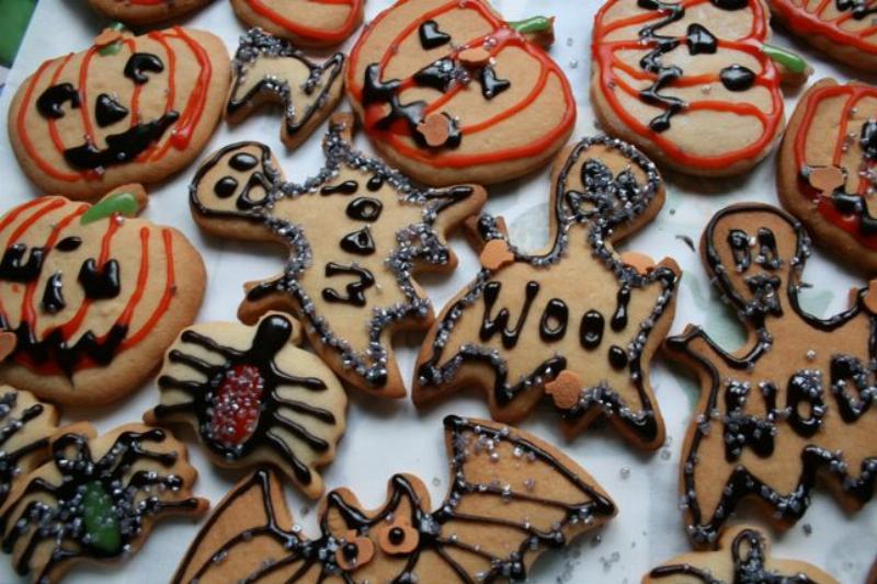 Decorating Halloween sugar cookies with royal icing and sprinkles.