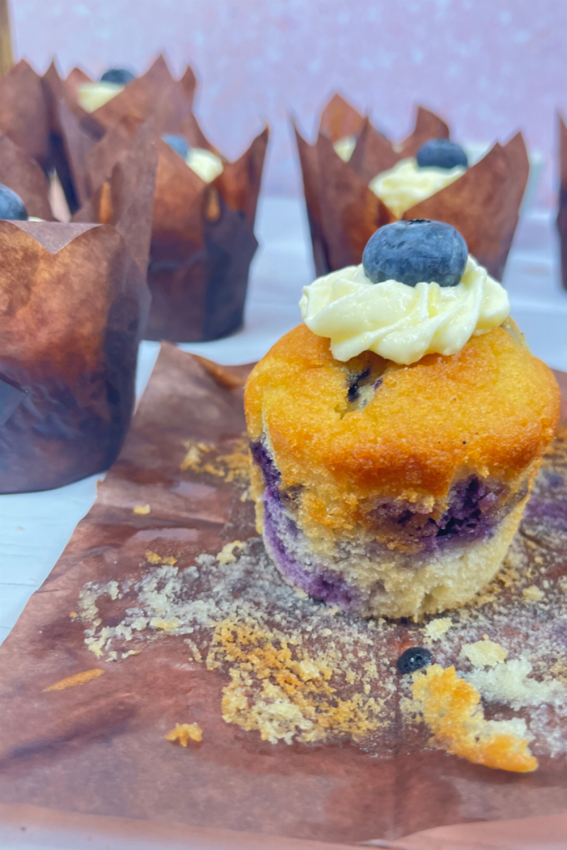 Frosted Keto Blueberry Cupcakes - Perfectly baked keto blueberry cupcakes topped with a swirl of cream cheese frosting, garnished with fresh blueberries.