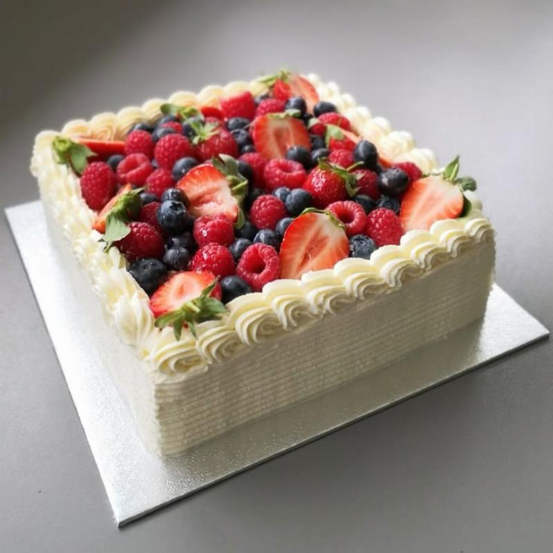 A layered sponge cake decorated with fresh berries and whipped cream