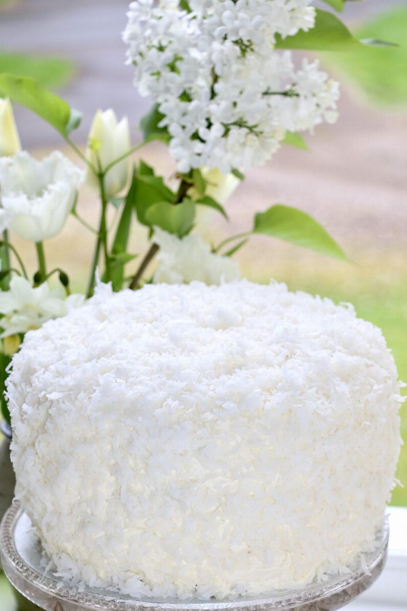 Moist coconut cake layers being frosted with coconut cream frosting