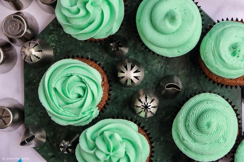 Piping a rosette design with whipped cream on a cupcake