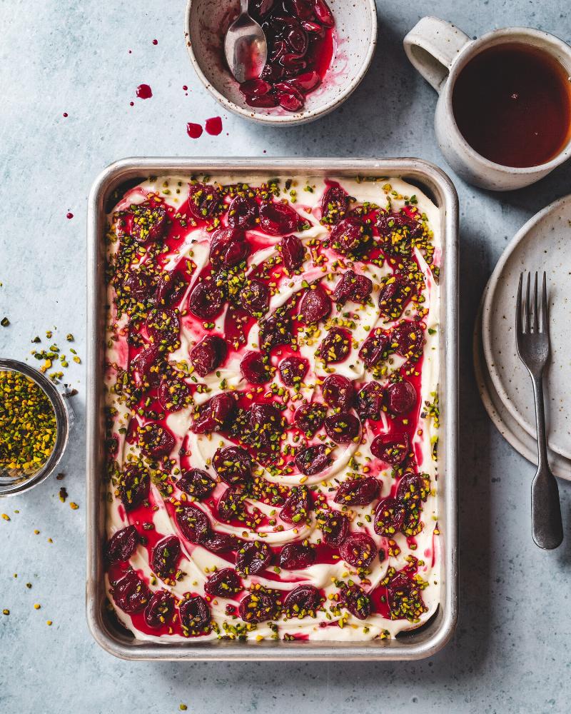 A beautiful pomegranate cake with cream cheese frosting, decorated with fresh pomegranate arils.