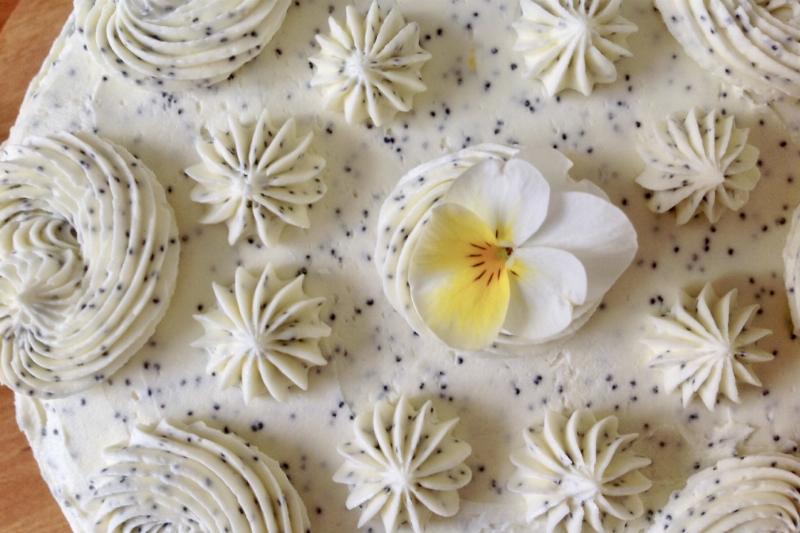 A cake frosted with smooth buttercream and decorated with fresh flowers