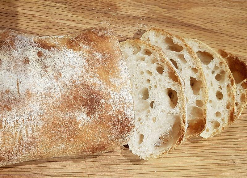 Close-up of a freshly baked sourdough loaf, showcasing its characteristic open crumb and blistered crust.