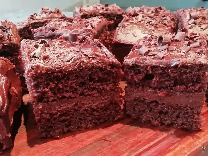 Slices of chocolate cake with various chocolate frostings, garnished with fresh berries and chocolate shavings.
