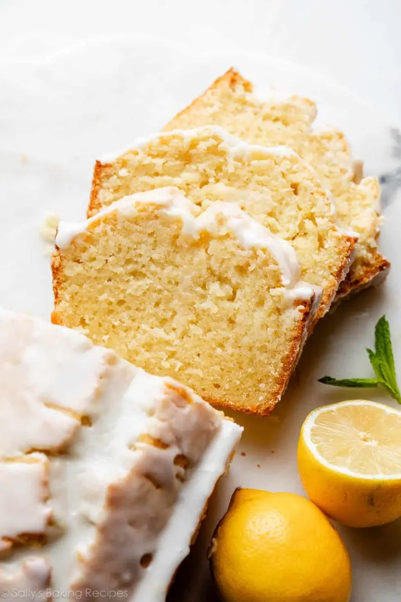 A slice of keto lemon pound cake drizzled with a thick, white citrus glaze, showing a moist crumb texture.