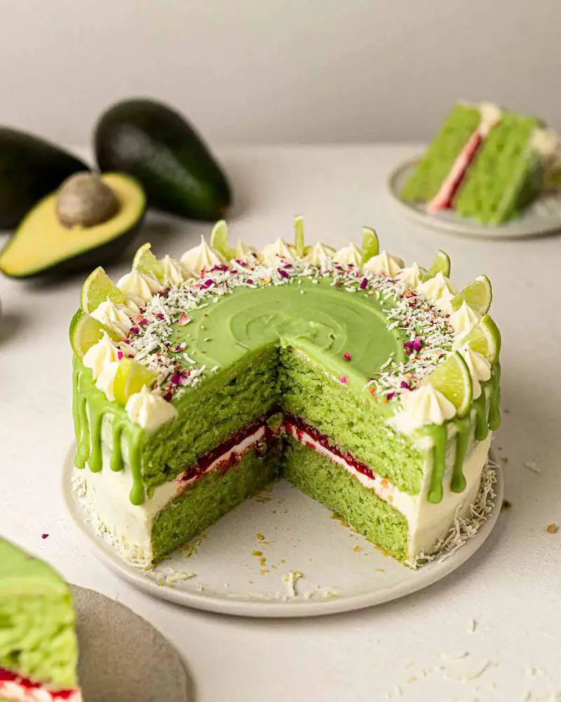 A small, round keto lime coconut cake covered in a slightly green-tinted glaze, with lime slices or zest on top.