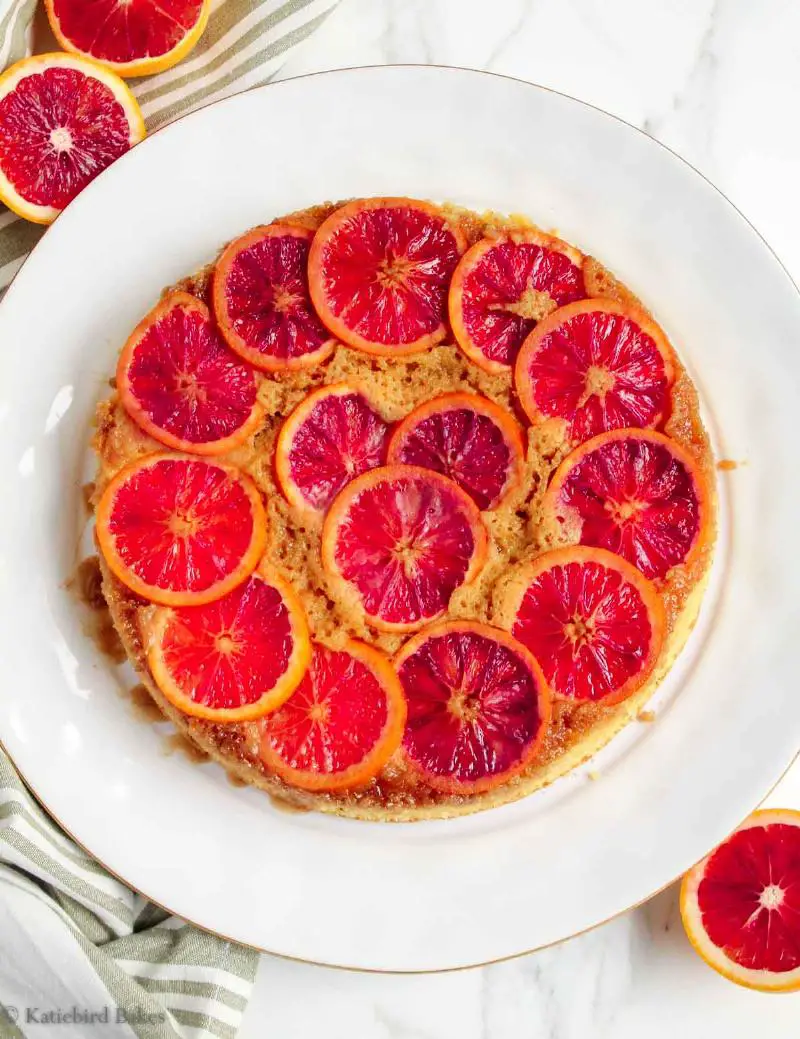 A close-up view of a keto orange almond cake slice topped with a thin citrus syrup glaze, showing the moist crumb and orange zest.
